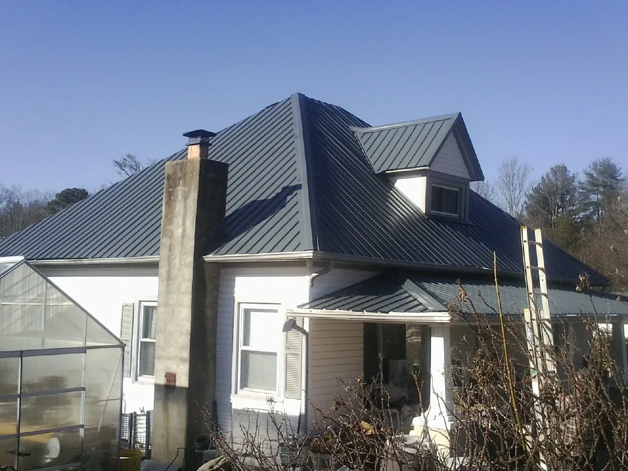 Dark blue standing seam metal roof on a white farmhouse with dormer — Slate & Tile Roof Repair by Roofing Brothers in Gilberts