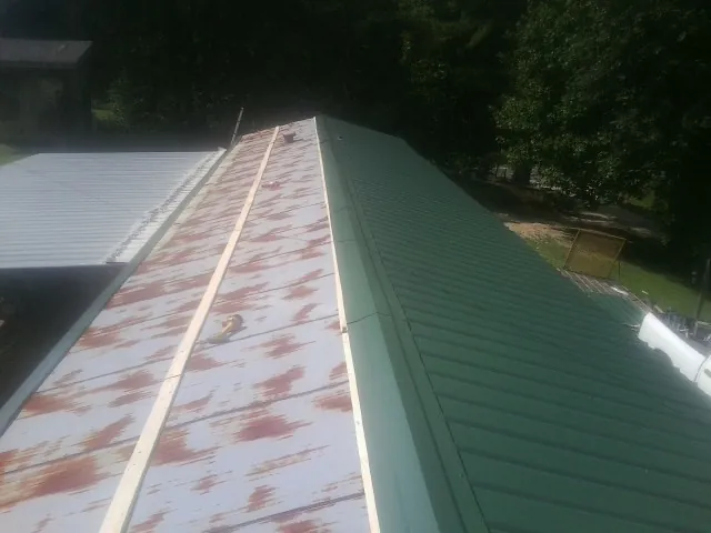 Old rusted panels beside newly installed green metal roofing — Wind Damage Roof Repair by Roofing Brothers in Gilberts