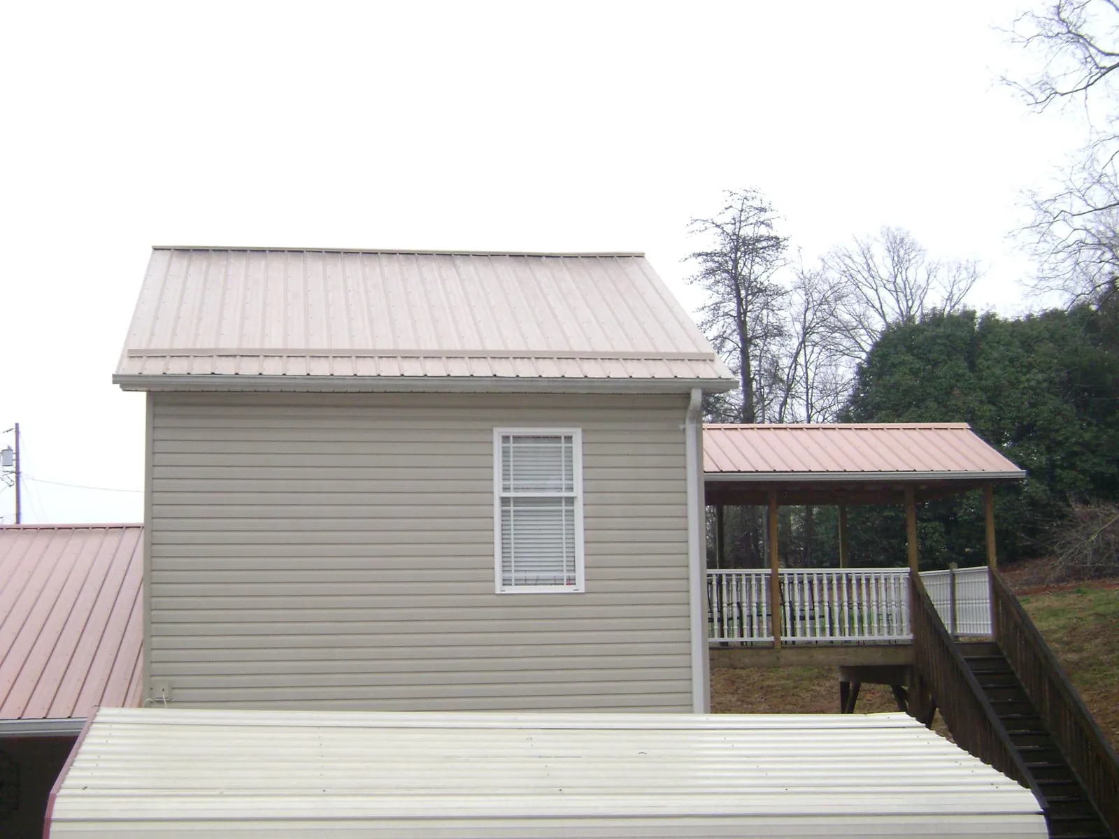 Tan metal roofs on a two story addition and attached porch, from a Roof Replacement job in Gilberts