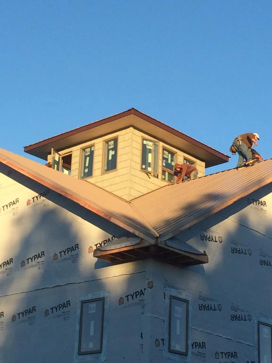 Roofers working around a rooftop cupola on a new metal roof at sunset — Roof Waterproofing in Gilberts by Roofing Brothers